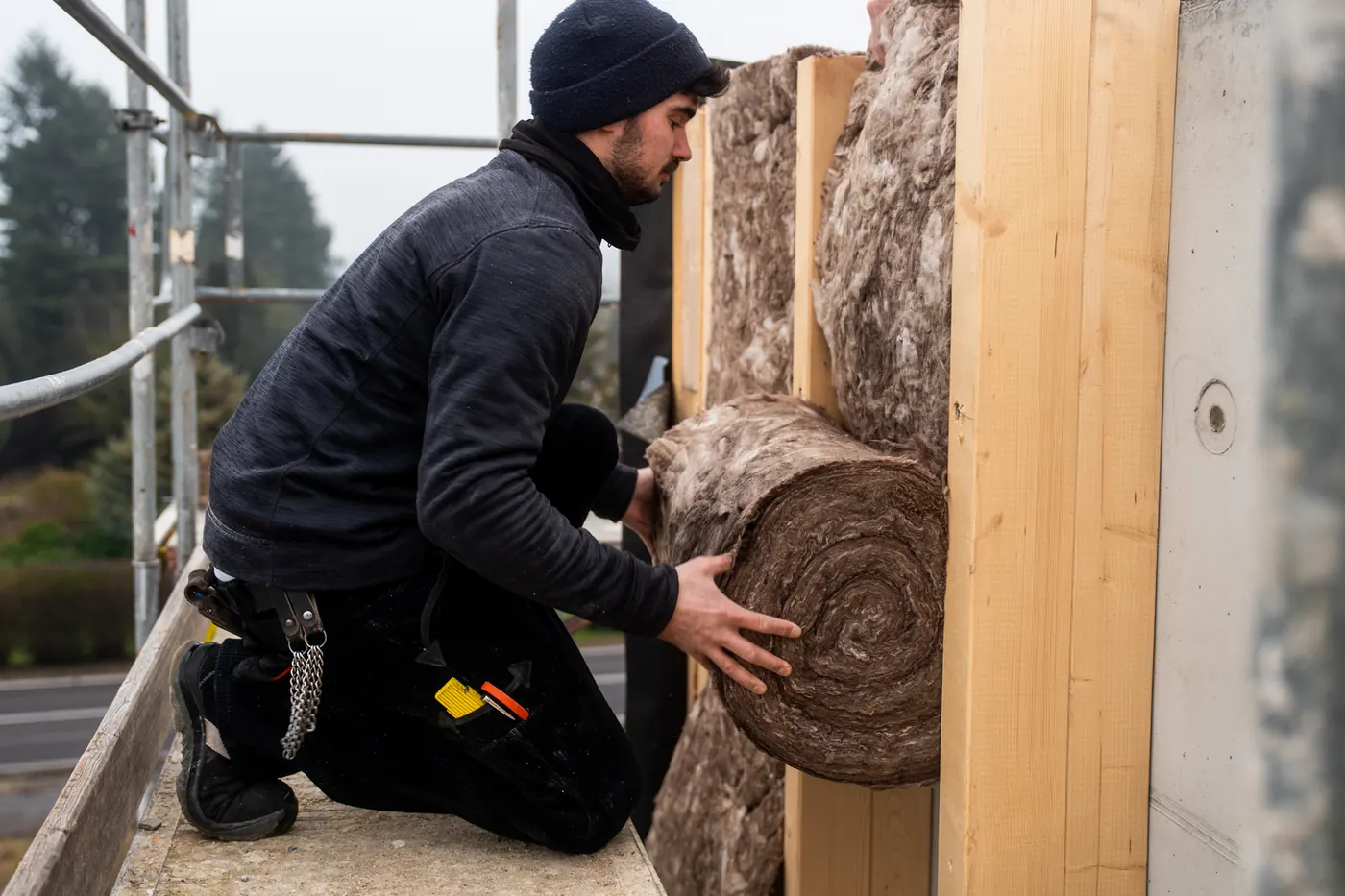 Zimmerer dämmt auf dem Gerüst eine Holzrahmenwand